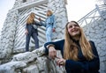 Group of three young Stylish nice girls in pantsuit costumes sitting on a stairs near white construction Royalty Free Stock Photo