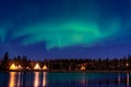 Group of Tipi under Aurora Borealis with smooth water reflection