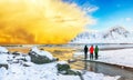 Group of tourist looking fabulous winter scenery on Skagsanden beach with illuminated clouds during sunrise