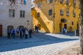 Group of tourists admiring the colorful medieval streets, the yellow house is the birtplace of Vlad Tepes also known as Dracula. Royalty Free Stock Photo