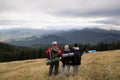 Group of tourists with backpacks in the mountains, back view, mountain range in the clouds, travel and tourism in the Royalty Free Stock Photo