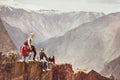 Group of tourists on cliff against mountains