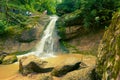 Group of tourists climb the mountain slope to the source of beautiful waterfall on river Mishoko