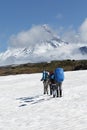 Group of tourists climbing the snowfield on background volcanoes