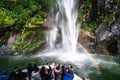 A group of tourists enjoying a stunning scene of nature while cruising into waterfall in Milford Sound, New Zealand. I