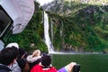 A group of tourists enjoying a stunning scene of nature while cruising into waterfall in Milford Sound, New Zealand. I