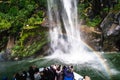 A group of tourists enjoying a stunning scene of nature while cruising into waterfall in Milford Sound, New Zealand. I