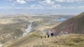 A group of tourists goes up the mountain. View from a height of the Alai Valley. Colored rocky mountains, lakes, rivers, green