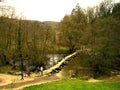 A group of tourists hiking, cross the ancient Tarr Steps Bridge.
