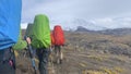 A group of tourists with large backpacks go to the snow-capped volcanoes of Kamchatka