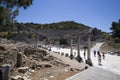 a group of tourists looking at the columns, ruins and amphitheater of the ancient city of Ephesus, surrounded by mountains