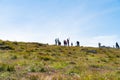 Group of tourists on ridge beyond slope against blue sky taking in views and photographing the Wild Atlantic Way