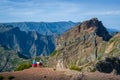 Group of tourists is sitting on the cliff and looking at the mountain landscape.