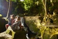 Group of tourists sitting on rocks looking at waterfall in thailand