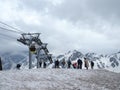 A group of tourists stands on the mountain at the lift and is photographed and admires the beautiful views of the snowy mountains