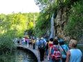 A group of tourists walking along a narrow path next to the insanely beautiful blue lake. Plitvice, Croatia- July 22, 2010