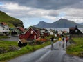 Group of tourists is walking in the rain in the small village of Gjogv, Faroe Islands.