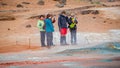 Group of tourists watching at geothermal active zone Hverir near Myvatn lake in Iceland, resembling Martian red planet landscape