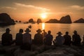 A group of tourists watching the sun set over Halong Bays magnificent seascape of limestone islands and karst mountains. Showcase