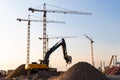 Group tower cranes, excavator silhouette at construction site, sunset sky background.Future residential high-rise complex Royalty Free Stock Photo