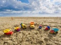 Group of toy working trucks of different sizes and colors arranged in a semicircle on the beach