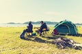 Group of travelers camping and doing picnic and playing music together. Mountain and lake background. People and lifestyle. Royalty Free Stock Photo