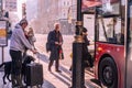 passengers with suitcases getting on a city bus at a station