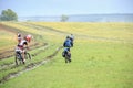 Group of travelling bikers with backpacks on dirty rural road after rain. Summer landscape with green hills Royalty Free Stock Photo