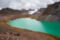 Group of trekker backpackers sitting relaxing at bank of Beautiful landscape of turquoise Ala-Kul Lake, Karakol valley, Issyk-kul Royalty Free Stock Photo