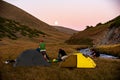 Group of trekkers camping in mountain pass. Climbers pitch tent in nature near Sary Chelek lake, Sary-Chelek Jalal Abad region,