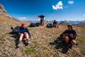 Group of trekkers resting and playing guitar in rocky pass with mountain top wiews in high mountains. Young men and women hiking