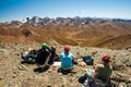 Group of trekkers resting in rocky pass with mountain top wiews in high mountains. Young men and women hiking near Sary Chelek