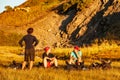 Group of trekkers resting in sunset sunbeams in high mountains. Young men and women hiking near Sary Chelek lake, Sary-Chelek