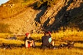 Group of trekkers resting in sunset sunbeams in high mountains. Young men and women hiking near Sary Chelek lake, Sary-Chelek