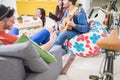 Group of trendy friends having fun in hostel living room - Happy young people enjoying time playing music and watching videos on