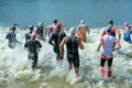 group triathlon participants running into the water for swim portion of race. Splash of water and athletes running.