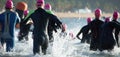 Group triathlon participants running into the water for swim portion of race