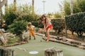 Group of two funny kids playing mini golf