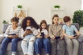 Group of unhappy children play online games or read social networks on mobile phones.