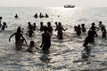 Silhouette of group of unidentified Indian pilgrims devotees women men children bathing in the sea, on the beach