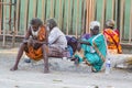 A Group of unidentified Sadhus pilgrims dressed in orange clothes, sitting in the street, on the road, waiting for food. It is a m