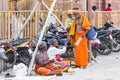 A Group of unidentified Sadhus pilgrims dressed in orange clothes, sitting in the street, on the road, waiting for food. It is a m