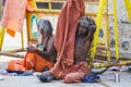 A Group of unidentified Sadhus pilgrims dressed in orange clothes, sitting in the street, on the road, waiting for food. It is a m