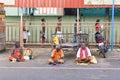 A Group of unidentified Sadhus pilgrims dressed in orange clothes, sitting in the street, on the road, waiting for food. It is a m