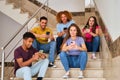 Group university students holding mobile phones and chatting at a break.