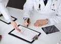 Group of unknown doctors are sitting at the desk and discussing medical treatment, using a clipboard, close-up. Team of