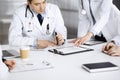 Group of unknown doctors are sitting at the desk and discussing medical treatment, using a clipboard, close-up. Team of