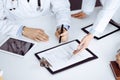 Group of unknown doctors are sitting at the desk and discussing medical treatment, using a clipboard, close-up. Team of