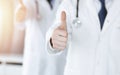 Group of unknown doctors standing as a team with thumbs up or Ok sign in hospital office, close-up. Medical help