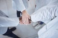 Group of unrecognisable scientists stacking and joining hands in unity and support while standing in a lab at work